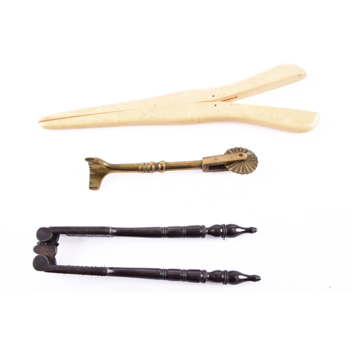 217 - A vintage brass pastry tool, a celluloid glove stretcher, together with a antique iron nut cracker. ... 