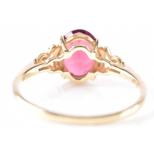 21 - A 9ct yellow gold garnet ring, featuring intricate openwork shoulders set with six small white stone... 