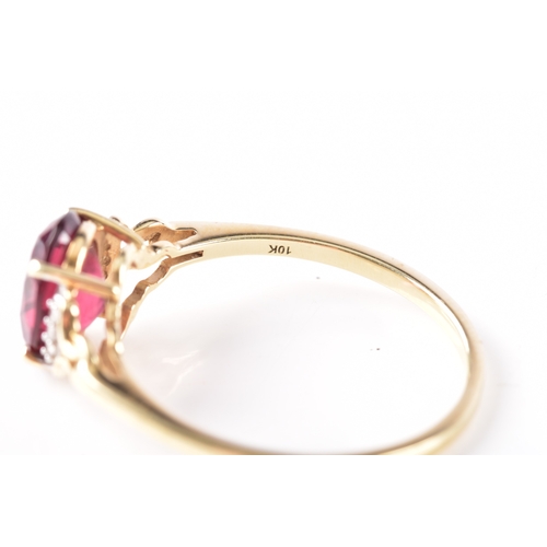 21 - A 9ct yellow gold garnet ring, featuring intricate openwork shoulders set with six small white stone... 