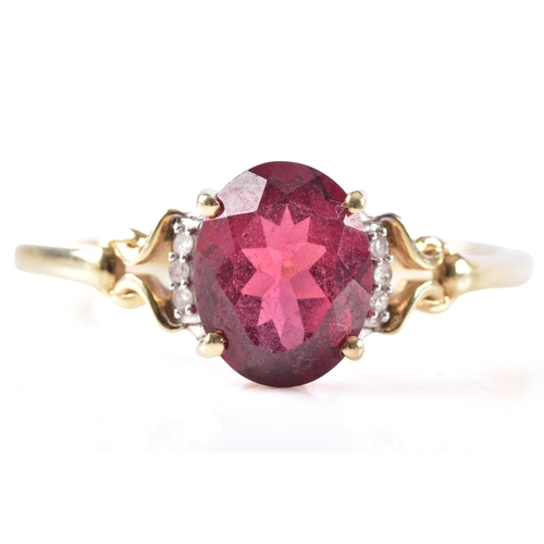 21 - A 9ct yellow gold garnet ring, featuring intricate openwork shoulders set with six small white stone... 