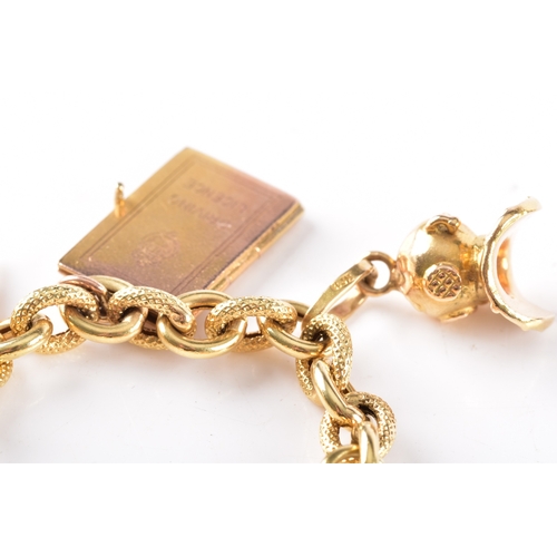 27 - An 18ct yellow gold charm bracelet, with alternating smooth and textured links, suspended with nine ... 