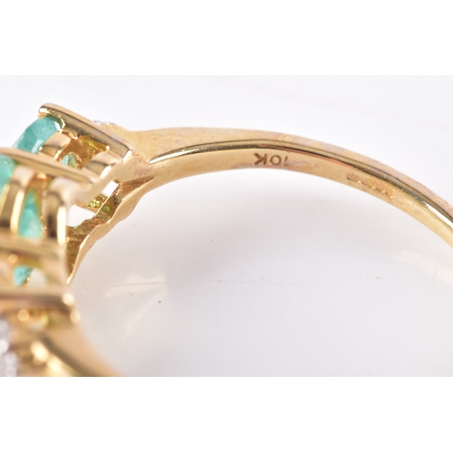 10 - A 9ct yellow gold and three stone emerald ring, the shoulders each set with three diamond accents, s... 