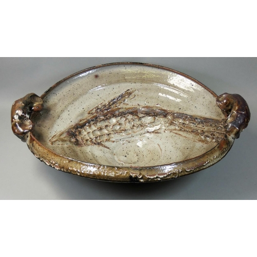 72 - Charles Bound (b.1939), a large twin-handled dish, with hand worked fish decoration, on a mottled cr... 