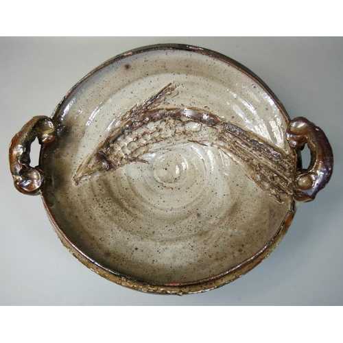 72 - Charles Bound (b.1939), a large twin-handled dish, with hand worked fish decoration, on a mottled cr... 