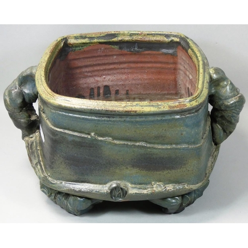 75 - Charles Bound (b.1939), a large irregular square twin handled stoneware container, on four arched fe... 