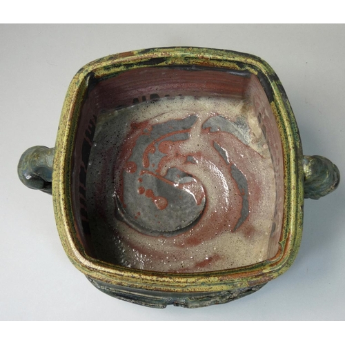 75 - Charles Bound (b.1939), a large irregular square twin handled stoneware container, on four arched fe... 