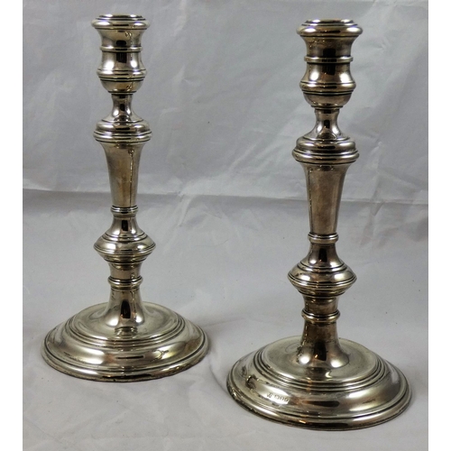 18 - A pair of silver candlesticks, London 1975, the cotton reel scones to a baluster stem with a circula... 