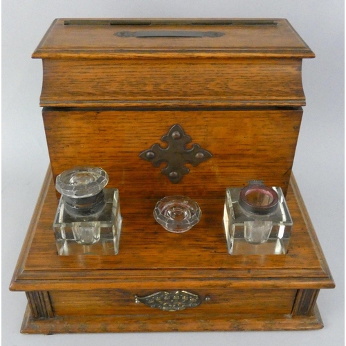 157 - An Edwardian oak desk stand, the hinged lid opening to reveal a fitted interior, two glass bottles, ... 