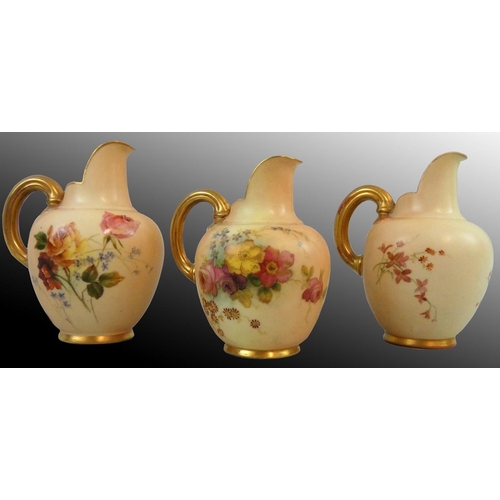 238 - A Royal Worcester blush ivory trio of flat-back jugs, each with gold gilt and floral decoration on a... 