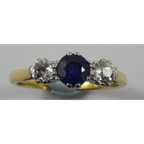 74 - An 18 ct gold sapphire and diamond three stone ring, claw set with an oval mixed cut stone flanked b... 