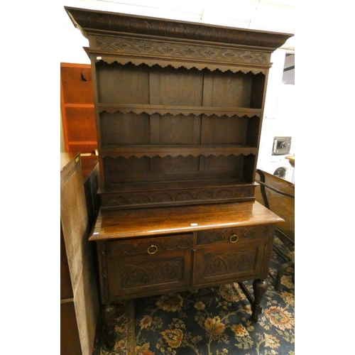 195 - A carved oak dresser with three shelf rack over two drawers and two cupboard doors raised on turned ... 