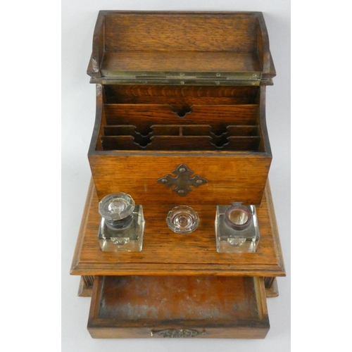 157 - An Edwardian oak desk stand, the hinged lid opening to reveal a fitted interior, two glass bottles, ... 