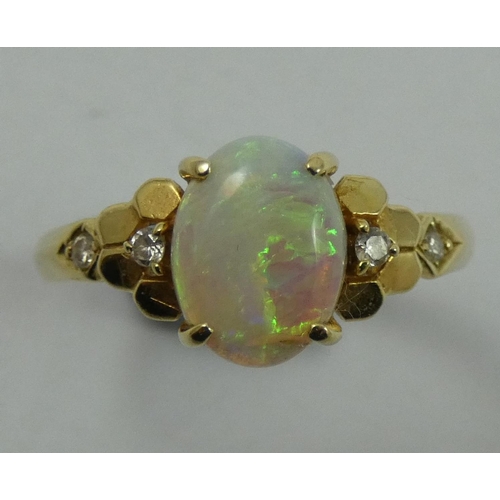 78 - A gold, opal and diamond dress ring, stamped 585, claw set with a cabochon stone flanked by brillian... 