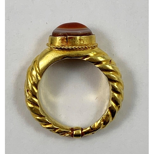 85 - A gold Roman style ring, collet set with a cabochon sardonyx, ribbed tapering shank, size W, weight ... 