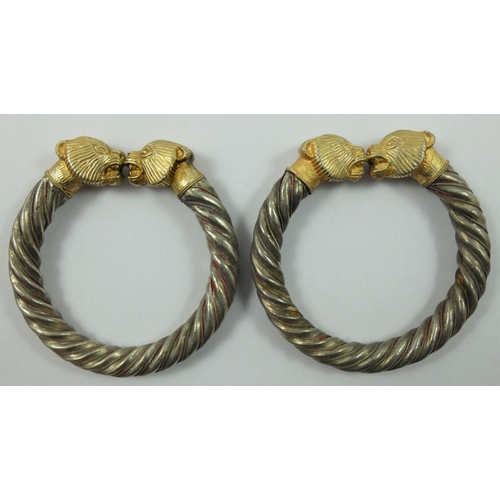 86 - A silver pair of Viking style hollow torque bangles, with gilt mythological animals head terminals, ... 