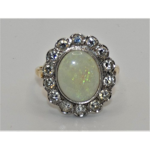 104 - An 18ct gold opal and diamond cluster ring, collet set with an oval stone, 12 x 10 mm, bordered by 1... 