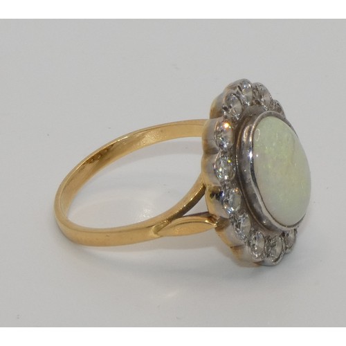 104 - An 18ct gold opal and diamond cluster ring, collet set with an oval stone, 12 x 10 mm, bordered by 1... 