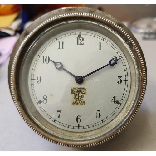 138 - A Smiths vintage dash board clock, silvered dial, hinged to allow winding, diameter 9 cm.