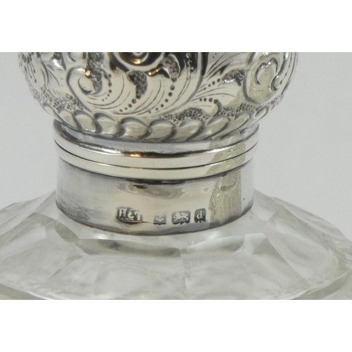 50 - A pair of silver capped cut glass scent bottles, Birmingham 1904, the embossed hinged covers (one br... 