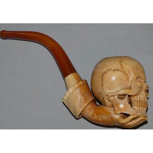 232 - A Victorian meerschaum pipe, carved in the form of a skull held by a hand, 17 cm.