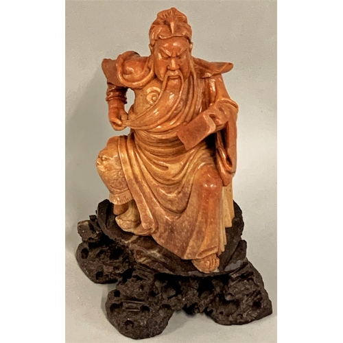 368 - A Chinese soapstone figure of a seated man reading a book, Qing dynasty, raised on a brown hardstone... 