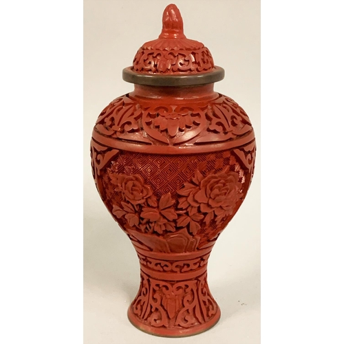 369 - A Chinese cinnabar lidded vase, carved with two floral panels, 17 cm.