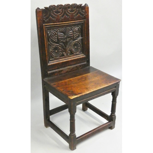 476 - An 18th century carved oak hall chair, with floral decorated back and stretcher supports, 95 cm.