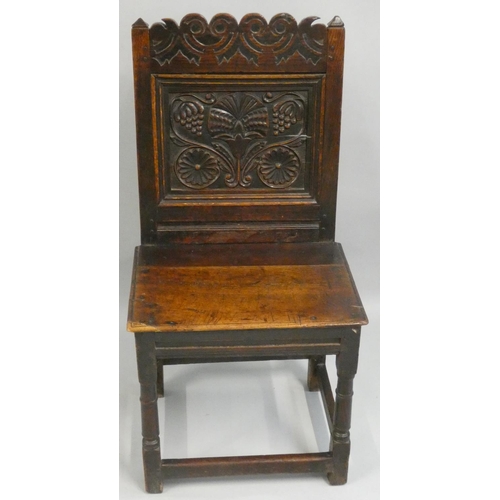 476 - An 18th century carved oak hall chair, with floral decorated back and stretcher supports, 95 cm.