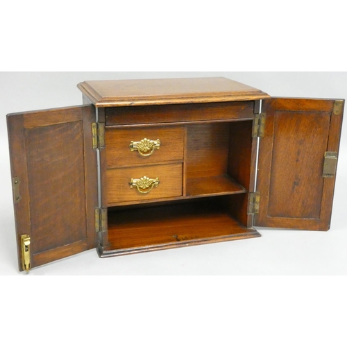 219 - An Edwardian oak smokers cabinet, the panel doors carved with floral decoration, opening to reveal t... 