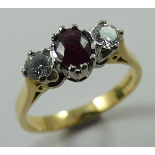 125 - An 18ct gold ruby and diamond three stone ring, claw set with an oval mixed cut stone flanked by bri... 