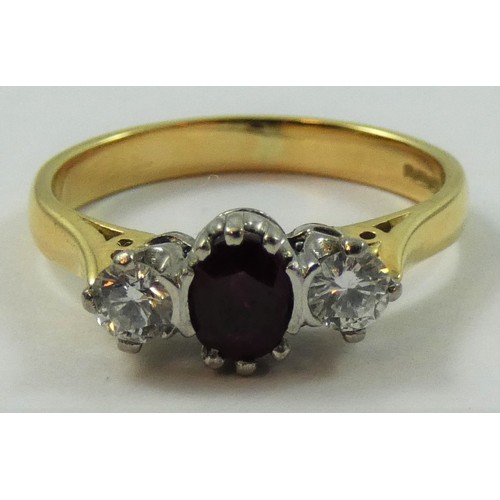 125 - An 18ct gold ruby and diamond three stone ring, claw set with an oval mixed cut stone flanked by bri... 