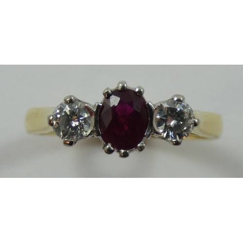 125 - An 18ct gold ruby and diamond three stone ring, claw set with an oval mixed cut stone flanked by bri... 