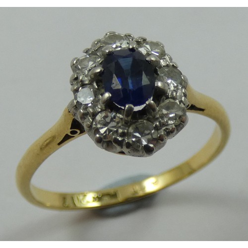 126 - An 18ct gold sapphire and diamond cluster ring, claw set with an oval mixed cut stone, bordered by e... 