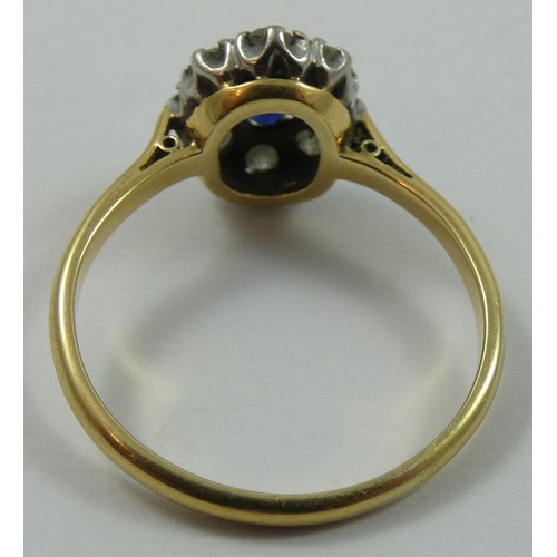 126 - An 18ct gold sapphire and diamond cluster ring, claw set with an oval mixed cut stone, bordered by e... 