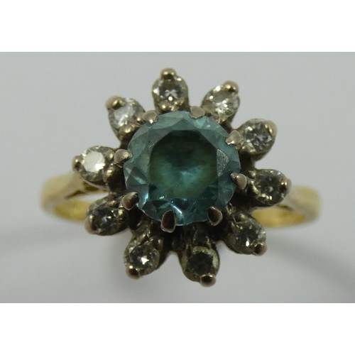 135 - A blue zircon and diamond cluster ring, claw set with a brilliant cut stone, bordered by ten brillia... 