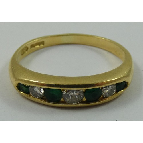 149 - An 18ct gold emerald and diamond seven stone ring, channel set with graduated brilliant cut stones, ... 