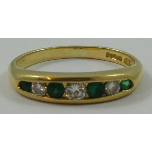 149 - An 18ct gold emerald and diamond seven stone ring, channel set with graduated brilliant cut stones, ... 