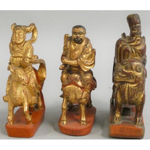 380 - Three Chinese carved and gilded wooden finials, Qing dynasty, a scholar mounted on a dragon, a man w... 