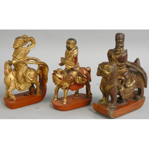 380 - Three Chinese carved and gilded wooden finials, Qing dynasty, a scholar mounted on a dragon, a man w... 