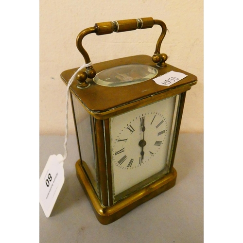 80 - A brass cased manual wind carriage clock with white enameled dial and roman numerals.