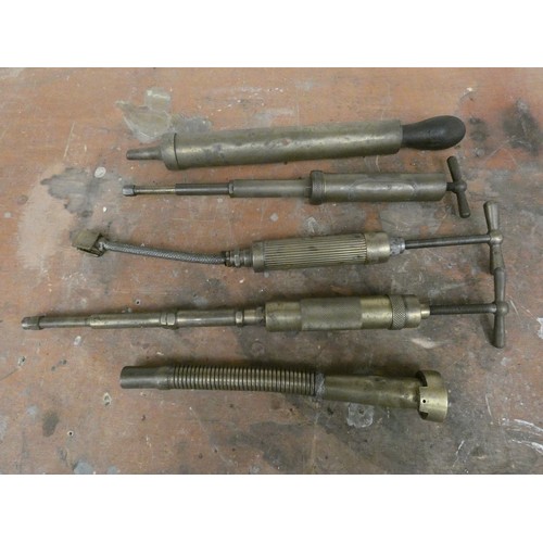 77 - Four brass grease guns and a brass petrol can pourer.