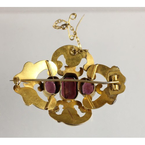 85 - A Victorian gold and garnet brooch, set with three graduated mixed cut stones  within an openwork sc... 