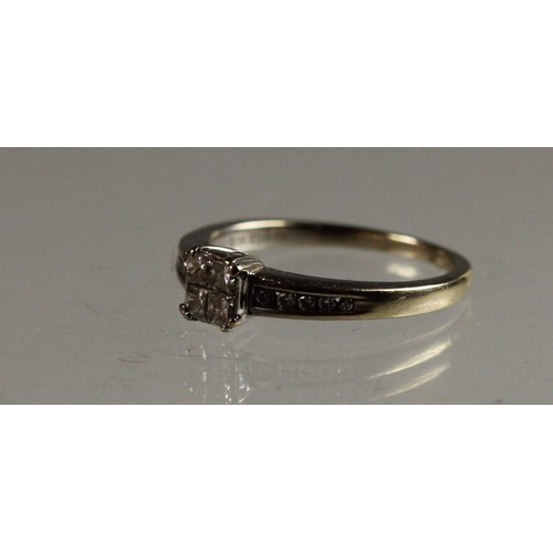 88 - An 18ct white gold diamond ring, claw set with four Princess cut stones, channel set brilliants to t... 