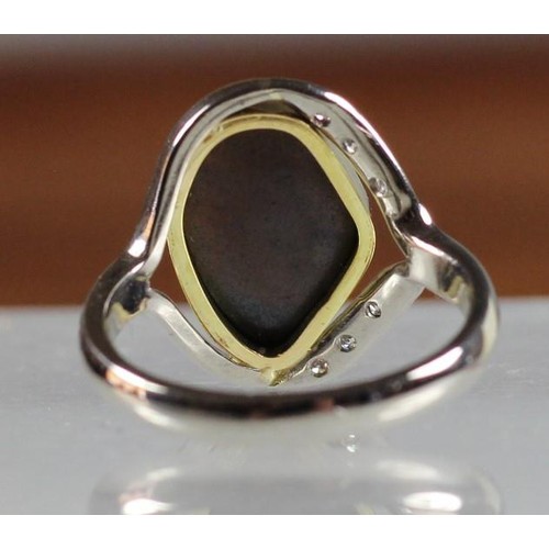 96 - An 18ct white gold Queensland black boulder opal and diamond ring, collet set with an irregular shap... 