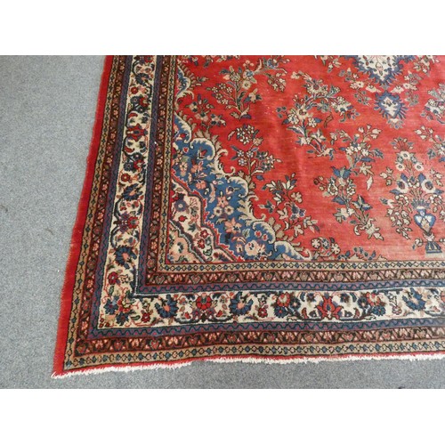 320 - A large Persian wool rug, decorated with a red field and foliage border, 400 x 320 cm