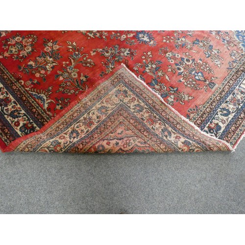 320 - A large Persian wool rug, decorated with a red field and foliage border, 400 x 320 cm