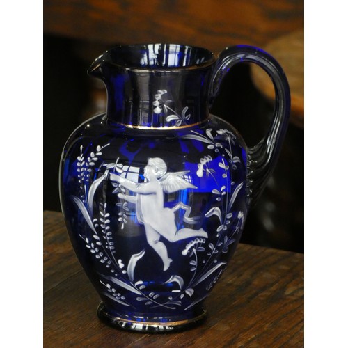110 - A cobalt blue glass jug with white cherub decoration together with a matching drinking glass