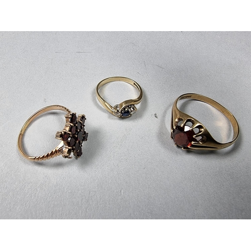 181 - A 9ct gold sapphire and diamond three stone ring, a 9ct gold garnet cluster ring and a 9ct gold sing... 