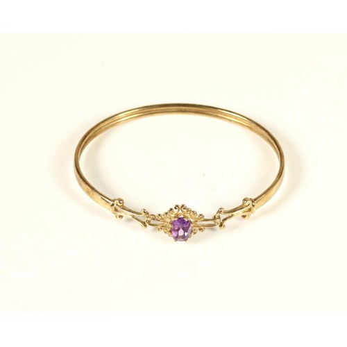 85 - A 9ct gold Victorian style sprung bangle, the scroll front set with a mixed cut amethyst, 6.2gm