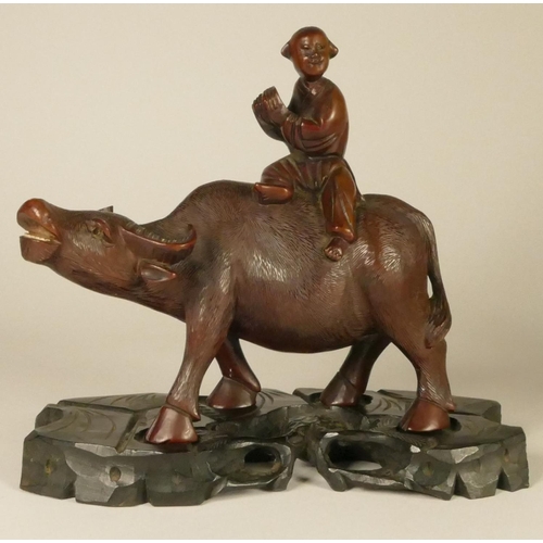 197 - A Chinese carved hard wood pair of figures, farmers seated upon water buffalo, raised on ebony bases... 